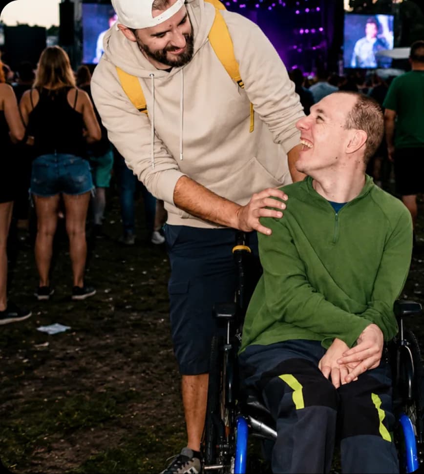 Iemand helpt op een festival een ander in een rolstoel.